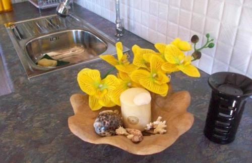 a vase with yellow flowers and a candle on a counter at One bedroom house at Albion 100 m away from the beach with shared pool enclosed garden and wifi in Albion