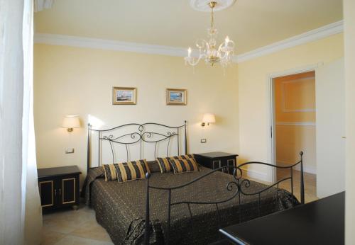 1 dormitorio con 1 cama negra con 2 mesas y lámpara de araña en 5 bedrooms villa with sea view private pool and enclosed garden at Montelabbate, en Montelabbate