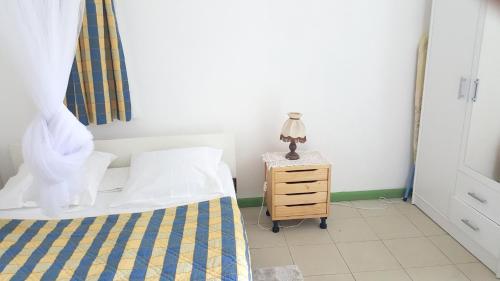 Un dormitorio con una cama y un tocador con una lámpara. en Appartement d'une chambre avec jardin clos et wifi a Baie Mahault, en Baie-Mahault