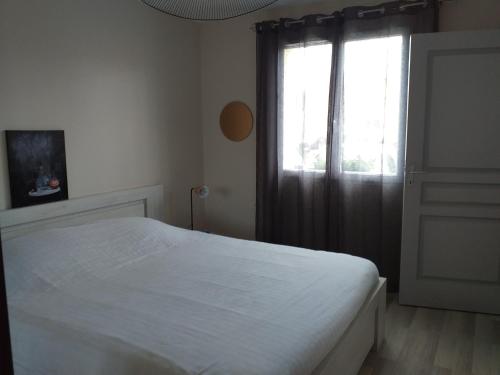 a bedroom with a white bed and a window at IDEAL 24H LE MANS in Mulsanne