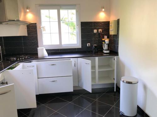 a kitchen with white cabinets and a window at Maison de 2 chambres avec piscine partagee terrasse amenagee et wifi a Sainte Rose in Sainte-Rose