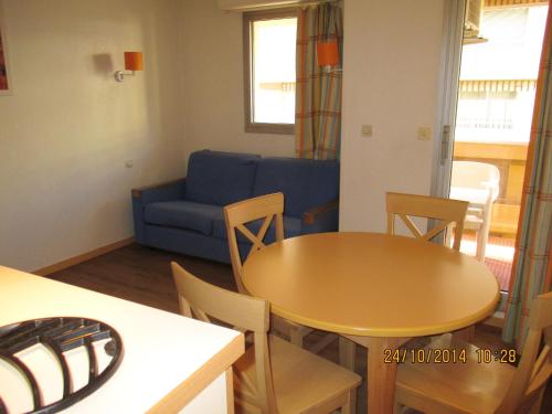 un salon avec une table et un canapé bleu dans l'établissement Studio moderne avec balcon – Saint-Raphaël – 25 m² – Parking, à Saint-Raphaël