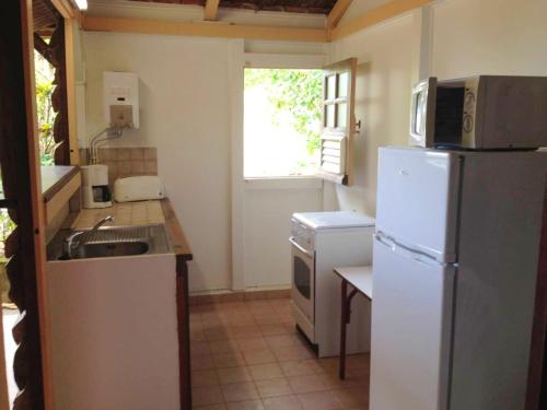 a kitchen with a white refrigerator and a sink at Studio avec vue sur la mer jardin clos et wifi a Les Trois Ilets in Les Trois-Îlets