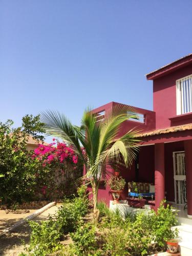 a palm tree in front of a pink building at Bright apartment with sea view and garden in Ouoran, 100 m² in Ouoran