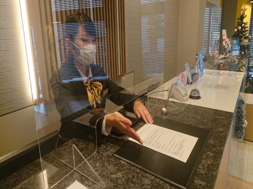 a man sitting on a counter with a paper on it at Smile Hotel Shizuoka Yoshida Inter in Yoshida