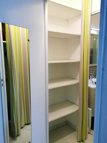 un placard avec des étagères blanches et un miroir dans l'établissement Studio charmant à Saint-Cyprien - 25 m² avec balcon, à Saint-Cyprien