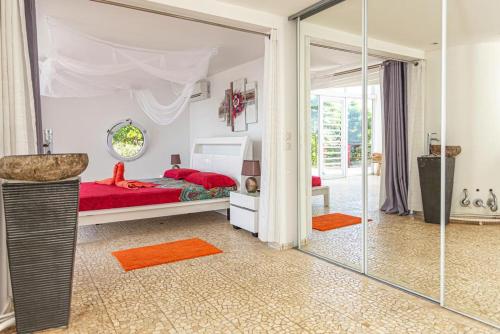1 dormitorio con cama roja y espejo en Villa de 2 chambres avec vue sur la mer piscine privee et jardin clos a Sainte Rose, en Sainte-Rose
