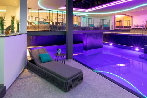 a swimming pool with a bench and purple lighting at Hotel Herrmann in Münsingen