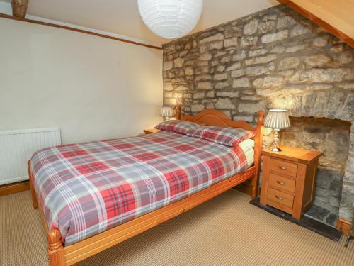 a bedroom with a bed and a stone wall at The Farmhouse in Ciliau-Aeron