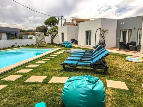 a house with a swimming pool and a blue chaise lounge at 4 bedrooms house with shared pool enclosed garden and wifi at Atalaia 3 km away from the beach in Lourinhã