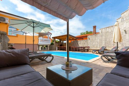um pátio com uma piscina, cadeiras e um guarda-sol em Villa Marko em Medulin