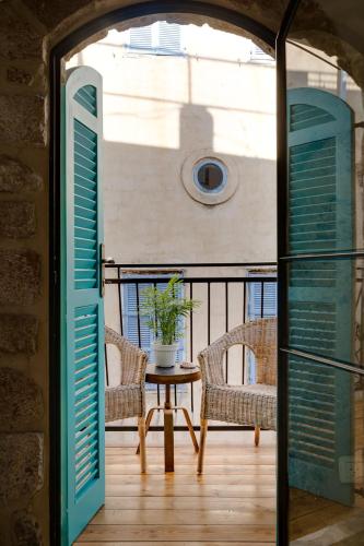 a balcony with a table and chairs and a window at Daya - Old City Acre in ‘Akko