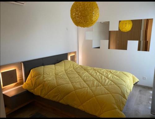 a bedroom with a bed with a yellow comforter at Appt Bouznika EDEN ISLAND pied sur Mer in Bouznika