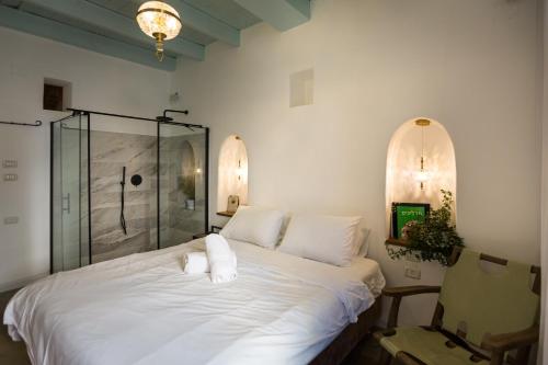 een slaapkamer met een wit bed en een glazen douche bij Daya - Old City Acre in Akko