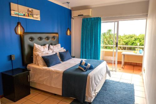 Un dormitorio con una cama grande con una pared azul. en L'escalier Cabanas 107, en Amanzimtoti