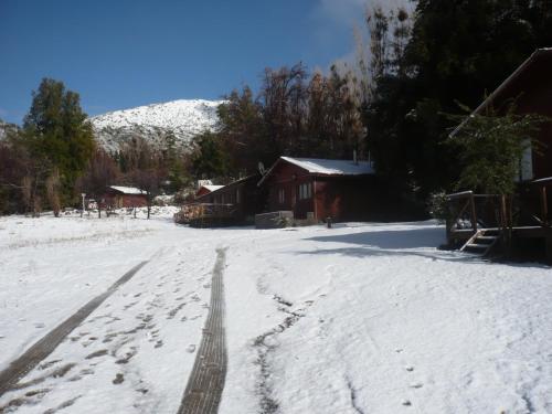 a snow covered road with a house and a mountain at El Parador de Caleu in Tiltil
