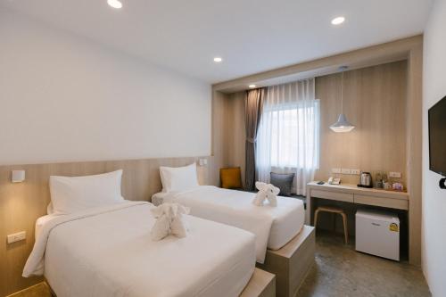 a hotel room with two beds and a desk at Nappiness Hotel - SHA ExtraPlus in Bangkok