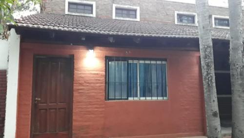 a small red house with a brown door at Hermosa Casita II Paso Patria in Paso de la Patria