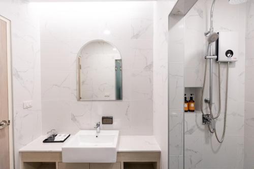 a white bathroom with a sink and a shower at Nappiness Hotel - SHA ExtraPlus in Bangkok