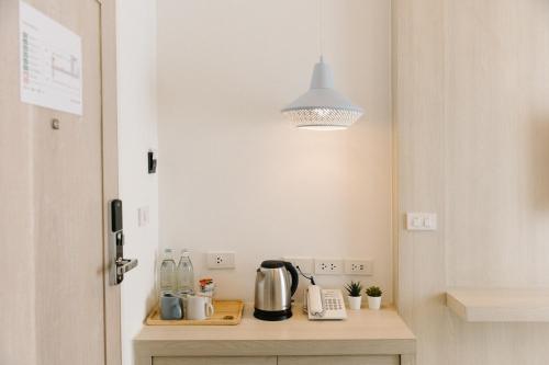 a kitchen with a table with a kettle and a light at Nappiness Hotel - SHA ExtraPlus in Bangkok