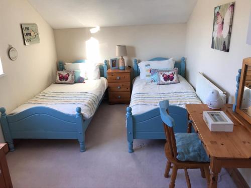 1 dormitorio con 2 camas y mesa de madera en Y Buarth, en Llansaint