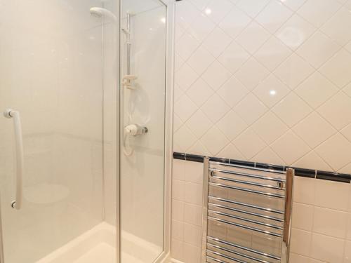 a shower with a glass door in a bathroom at Jackson Cottage in Alnwick