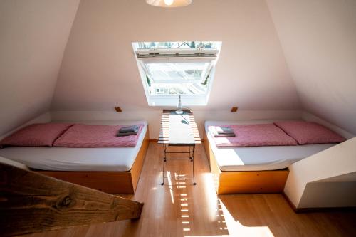 a attic room with two beds and a window at Black Forest Bike Hostel in Kirchzarten