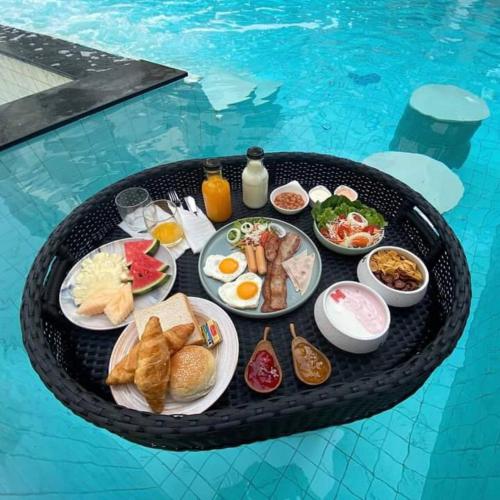 a tray of breakfast food on a table in a swimming pool at Mandarin Eastville, Pattaya - SHA Extra Plus in Pattaya North