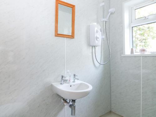 a white bathroom with a sink and a shower at Pier Cottage in Saint Mawes