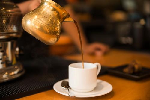a person pouring coffee into a cup on a table at Grand Mercure Bengaluru at Gopalan Mall - An Accor Brand in Bengaluru