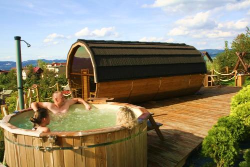 a man and a woman in a hot tub at Osada Na Ochodzitej in Koniaków