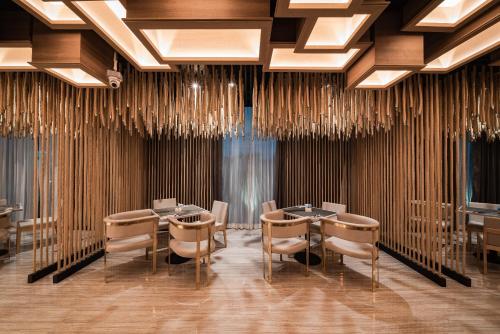 a dining room with tables and chairs and chandeliers at Mandarin Eastville, Pattaya - SHA Extra Plus in Pattaya North