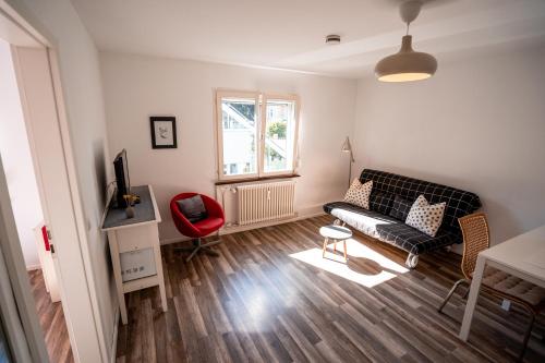 a living room with a black couch and a red chair at Black Forest Bike Hostel in Kirchzarten