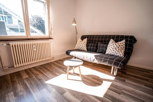 a living room with a black couch and a table at Black Forest Bike Hostel in Kirchzarten
