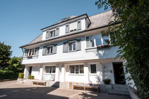 a white building with windows on a street at Black Forest Bike Hostel in Kirchzarten