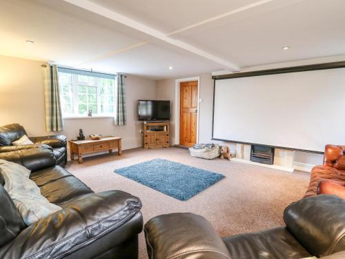 a large screen in a living room with leather furniture at Fisher Granary in Lampeter
