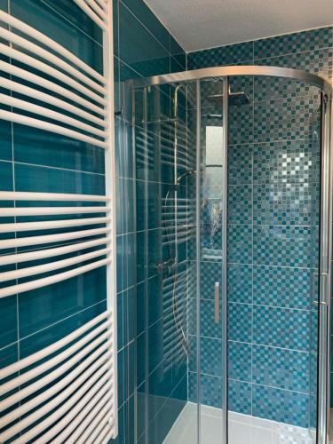 a bathroom with a shower with blue tiles at Strandperle 83 in Julianadorp