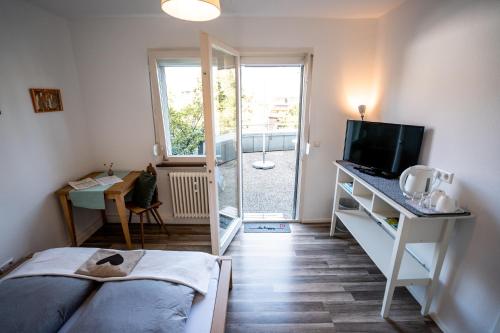 a bedroom with a bed and a desk with a television at Black Forest Bike Hostel in Kirchzarten