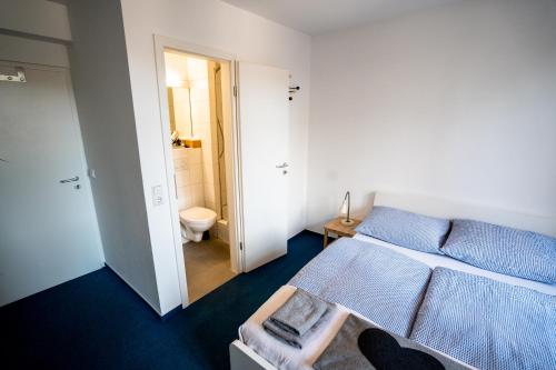 a small room with a bed and a bathroom at Black Forest Bike Hostel in Kirchzarten
