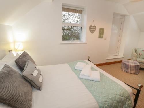 a bedroom with a large white bed and a window at Hen Stabl in Llanrwst