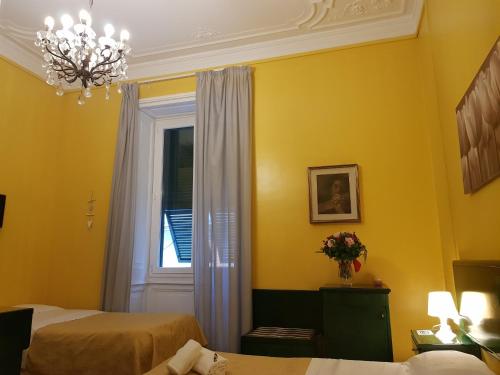 Habitación amarilla con 2 camas y ventana en Hotel Suisse, en Génova