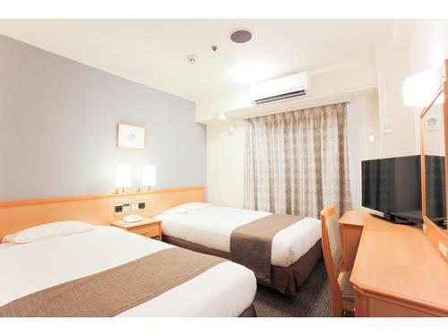 和歌山市にあるスマイルホテル和歌山のベッド2台、薄型テレビが備わるホテルルームです。