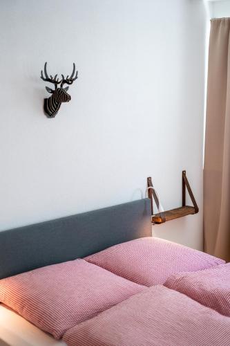 a bedroom with a bed with a antelope head on the wall at Black Forest Bike Hostel in Kirchzarten
