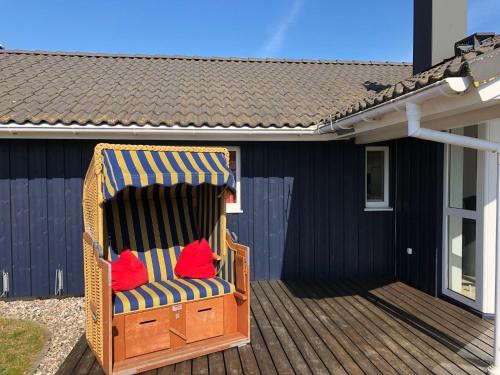 a chair with red pillows sitting on a deck at Strandhus - Haus 37 in Grömitz