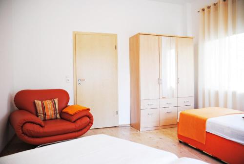 a bedroom with a red chair and a bed at Appartementanlage-Ferienwohnungen Weiße Möwe in Sassnitz