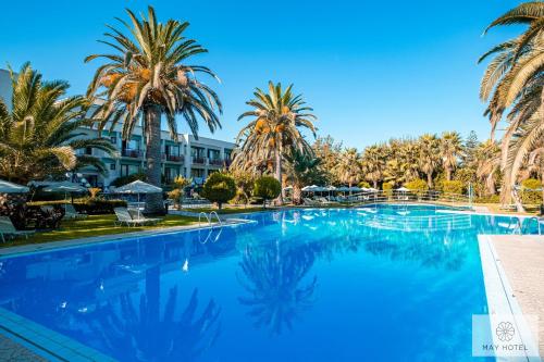 una gran piscina con palmeras en el fondo en May Beach Hotel, en Rethymno