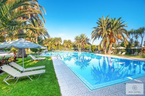 a large swimming pool with chairs and palm trees at May Beach Hotel in Rethymno Town