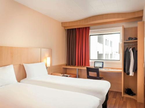 a hotel room with two beds and a desk and a window at ibis Paris la Défense Esplanade in Courbevoie