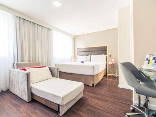 a hotel room with two beds and a chair at Mercure Sao Paulo Vila Olimpia in São Paulo