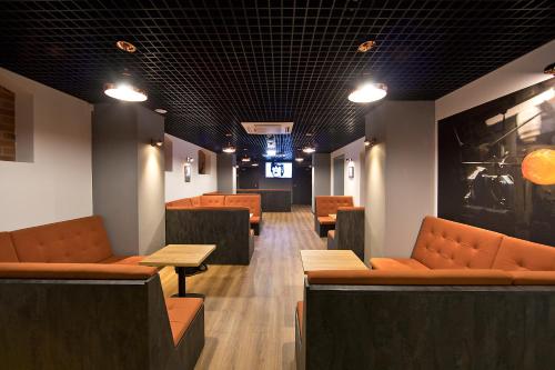 a waiting room with orange couches and tables at Hotel Stronie in Stronie Śląskie